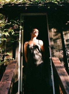 portrait of Chi Adi standing in a doorway surrounding by foliage